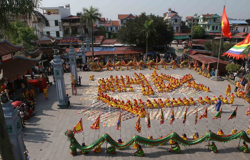  Các thanh niên nam nữ trong làng sẽ mặc áo cánh vàng, quần trắng, thắt lưng vải đỏ thắt múi đầu rìu, đầu buộc khăn lụa theo sự chỉ huy của các Tổng cờ sẽ lần lượt xếp thành chữ “Mẫu nghi thiên hạ.” (Ảnh: Công Luật/TTXVN)