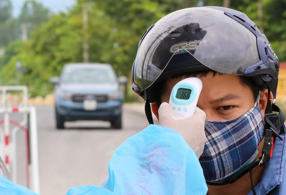 Các chốt kiểm dịch tiến hành đo thân nhiệt người tham gia lưu thông tại các vùng dịch ở xã Hòa Tiến. (Ảnh: Trần Lê Lâm/TTXVN)