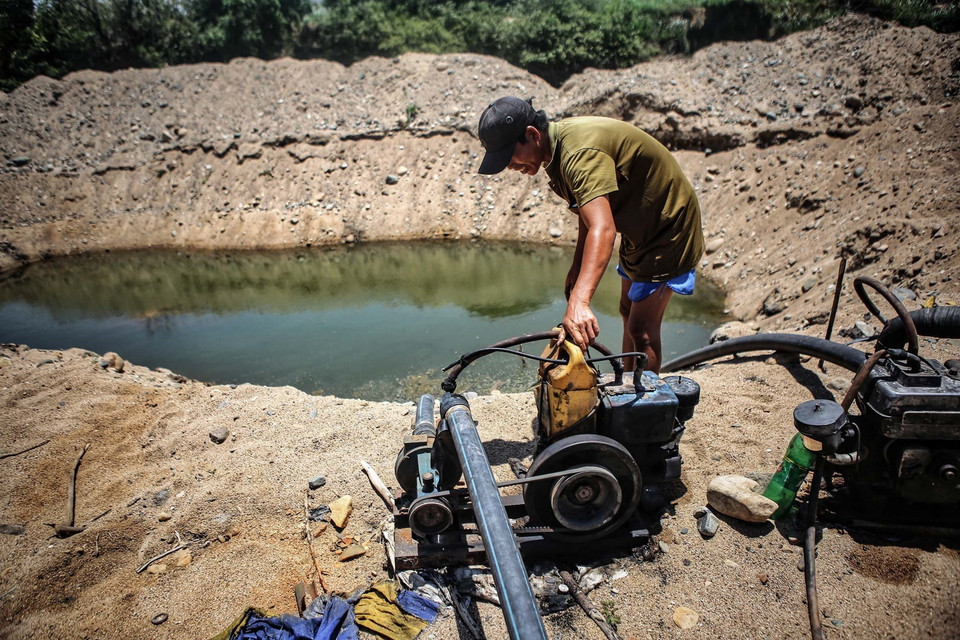 Người dân bơm nước từ những hố được đào sâu xuống đáy sông Lu, huyện Thuận Nam để lấy nước sinh hoạt và tưới tiêu do hạn hán kéo dài. (Ảnh: TTXVN)