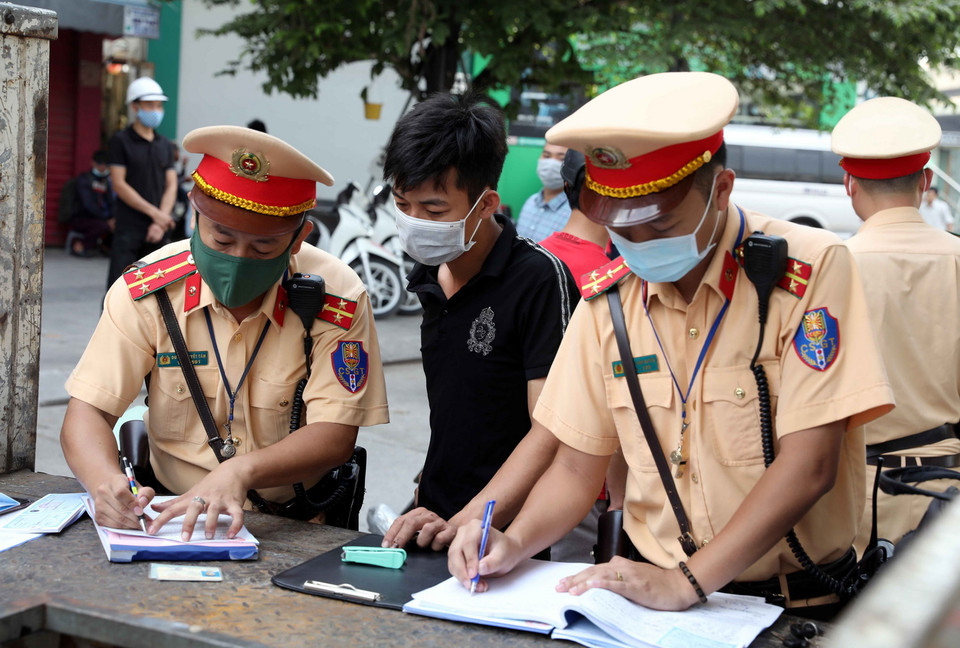  Cán bộ Đội CSGT số 7 xử phạt các trường hợp không đội mũ bảo hiểm khi tham gia giao thông tại ngã tư Khuất Duy Tiến-Nguyễn Trãi. (Ảnh: Phạm Kiên/TTXVN)