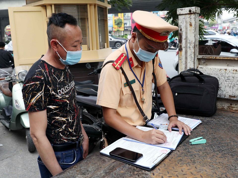  Cán bộ Đội CSGT số 7 xử phạt các trường hợp không đội mũ bảo hiểm khi tham gia giao thông tại ngã tư Khuất Duy Tiến-Nguyễn Trãi. (Ảnh: Phạm Kiên/TTXVN)