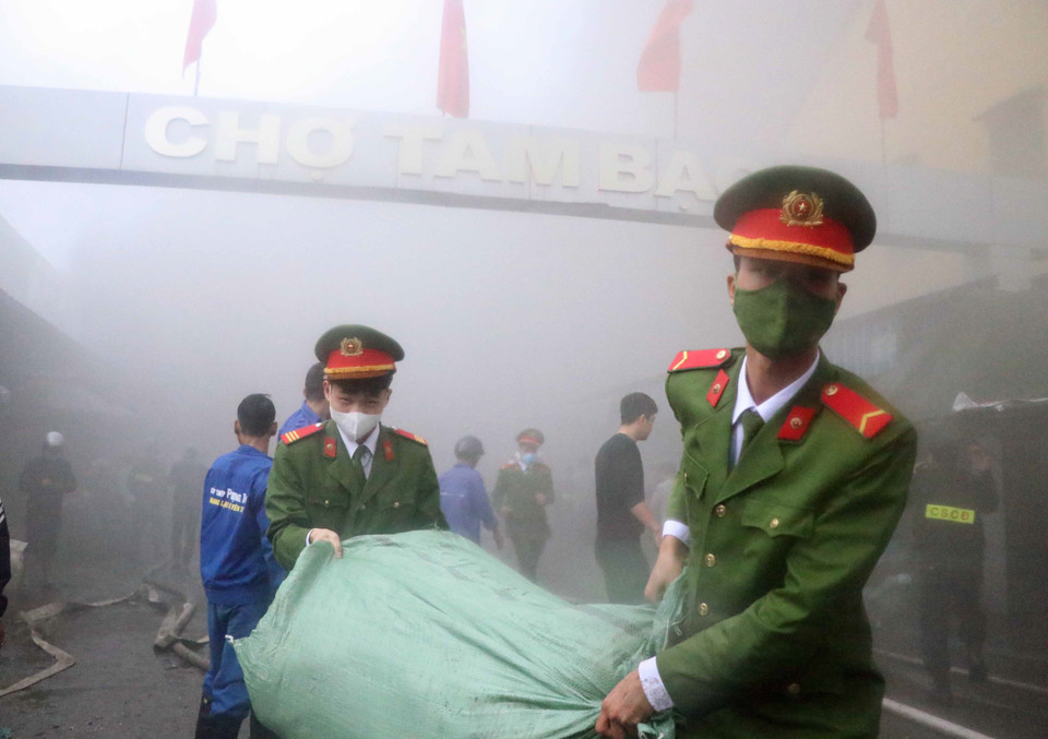 Lực lượng chữa cháy và người dân sơ tán tài sản khỏi hiện trường. (Ảnh: Hoàng Ngọc/TTXVN)