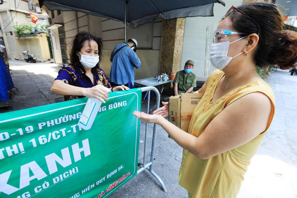 Tổ phòng, chống COVID cộng đồng tại chốt Vùng xanh ngõ Hà Trung, phường Hàng Bông xịt tay khử khuẩn cho mỗi người dân mỗi khi ra vào. (Ảnh: Thành Đạt/TTXVN)