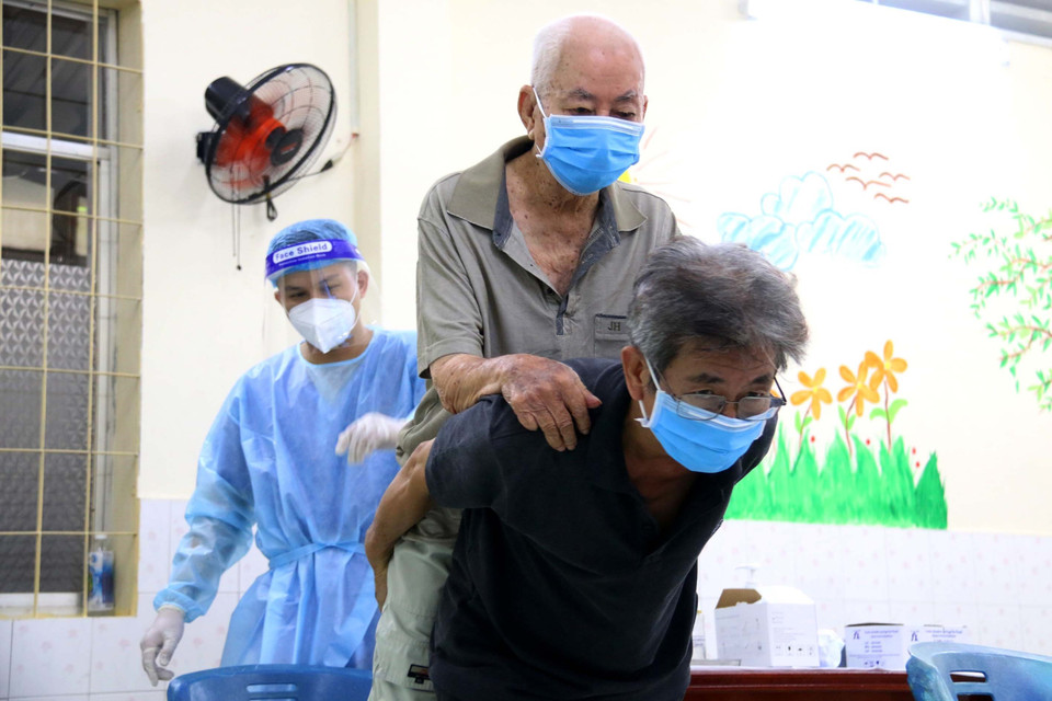 Một cụ ông được người nhà đưa đến điểm tiêm. (Ảnh: Thanh Vũ/TTXVN)