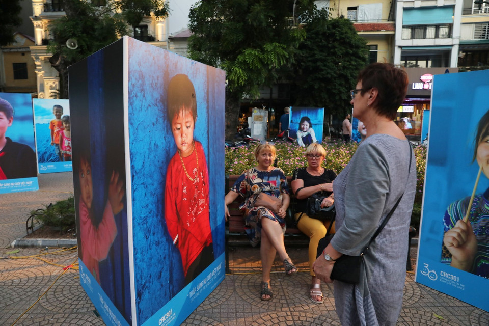 Du khách quốc tế tham quan triển lãm ảnh Thắp sáng nụ cười Việt Nam. (Ảnh: Thành Đạt/TTXVN)