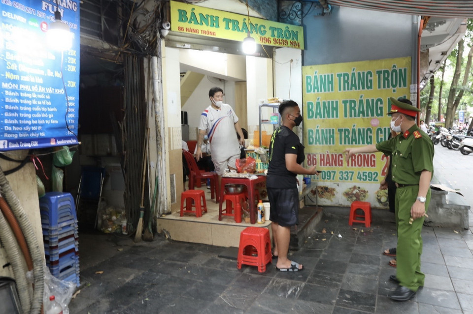 Lực lượng chức năng nhắc nhở các hộ kinh doanh thực hiện nghiêm Công điện của Chủ tịch UBND thành phố Hà Nội. (Ảnh: Minh Quyết/TTXVN