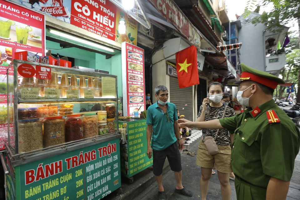  Lực lượng chức năng nhắc nhở các hộ kinh doanh thực hiện nghiêm Công điện của Chủ tịch UBND Thành phố Hà Nội. (Ảnh: Minh Quyết/TTXVN)