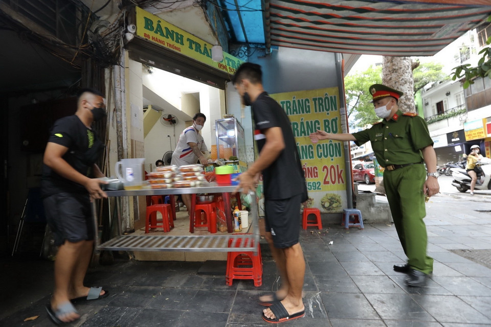 Lực lượng chức năng nhắc nhở các hộ kinh doanh thực hiện nghiêm Công điện của Chủ tịch UBND thành phố Hà Nội. (Ảnh: Minh Quyết/TTXVN