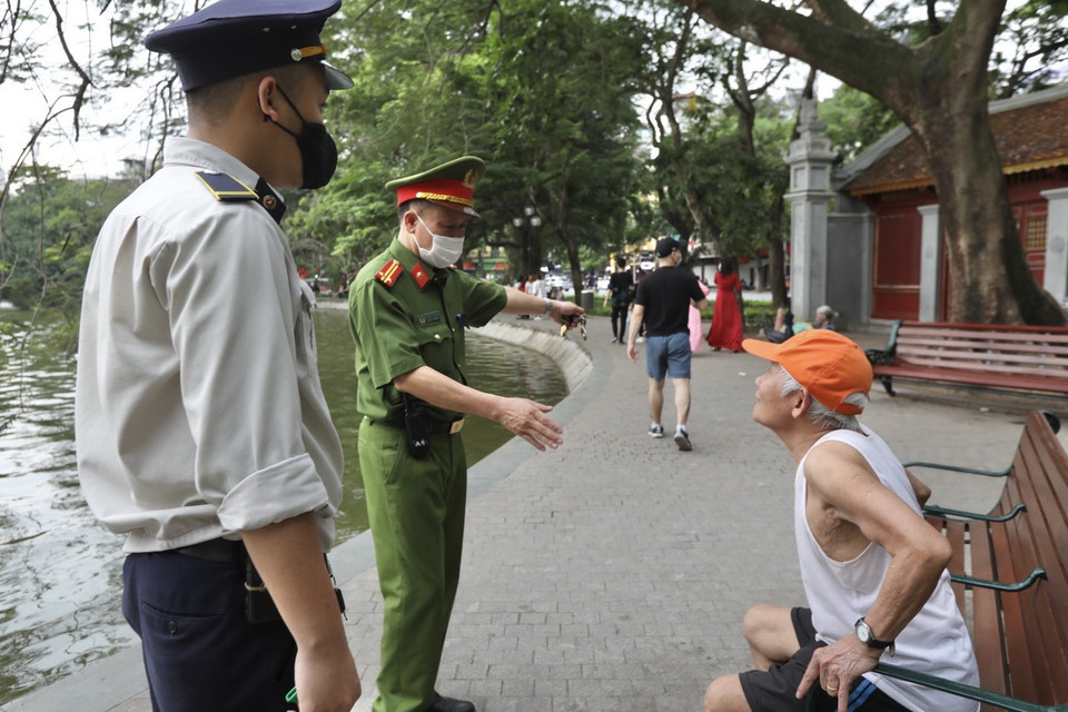 Lực lượng chức năng nhắc nhở người dân thực hiện nghiêm công điện của Chủ tịch UBND thành phố. (Ảnh: Minh Quyết/TTXVN)