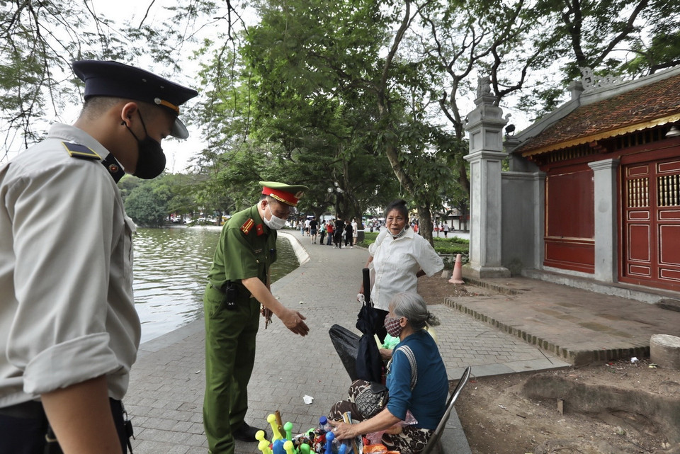 Lực lượng chức năng nhắc nhở người dân thực hiện nghiêm công điện của Chủ tịch UBND thành phố. (Ảnh: Minh Quyết/TTXVN)
