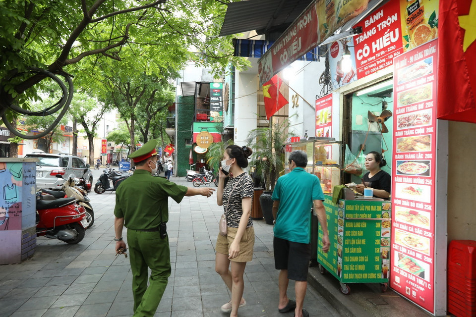 Lực lượng chức năng nhắc nhở các hộ kinh doanh thực hiện nghiêm Công điện của Chủ tịch UBND thành phố Hà Nội. (Ảnh: Minh Quyết/TTXVN)