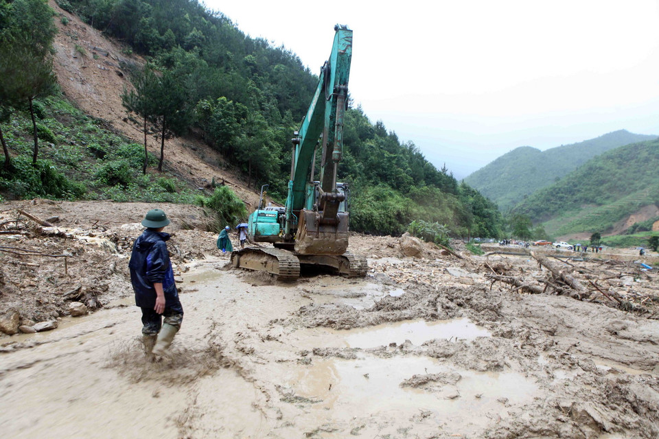 Các lực lượng chức năng đang khẩn trương khắc phục đoạn đường Quốc lộ 4D tại Km 73 do lượng đất đá vùi lấp khiến tuyến đường tiếp tục bị tê liệt. (Ảnh: Quý Trung/TTXVN)