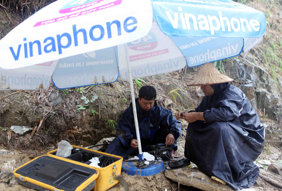 Cán bộ công nhân viên của tập đoàn viễn thông đang xử lý sự cố do mưa lũ gây ra qua Quốc lộ 4D tại Km75. (Ảnh: Quý Trung/TTXVN)