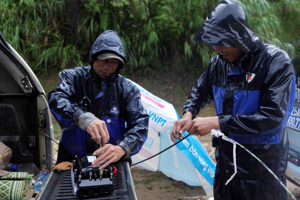 Cán bộ công nhân viên của tập đoàn viễn thông xử lý sự cố do mưa lũ gây ra qua Quốc lộ 4D tại Km75. (Ảnh: Quý Trung/TTXVN)