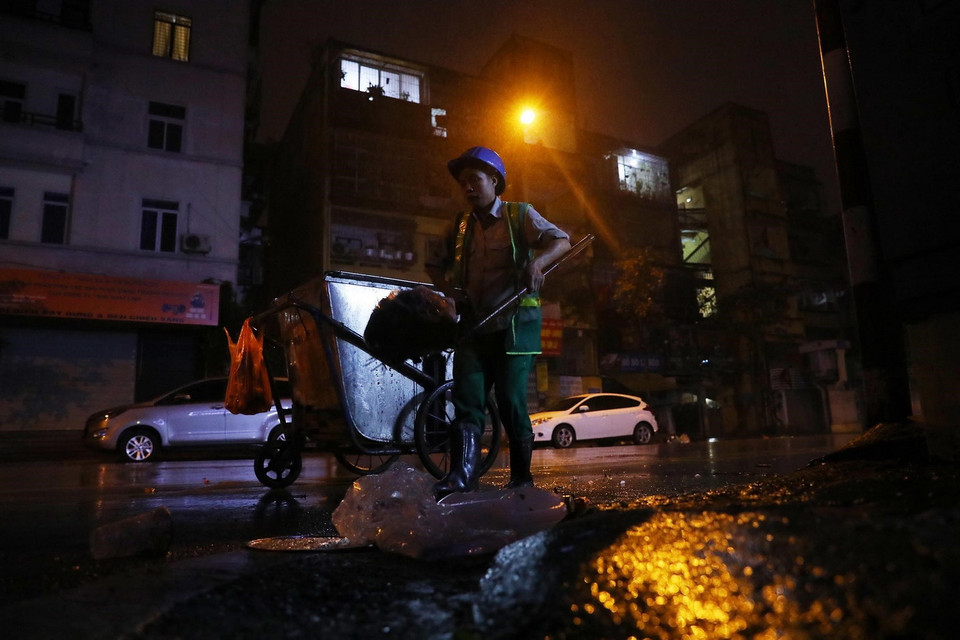 Một nhân viên Đội 5, Xí nghiệp Môi trường đô thị số 3 thu gom rác thải trên phố Thanh Nhàn, quận Hai Bà Trưng. (Ảnh: Lâm Khánh/TTXVN)