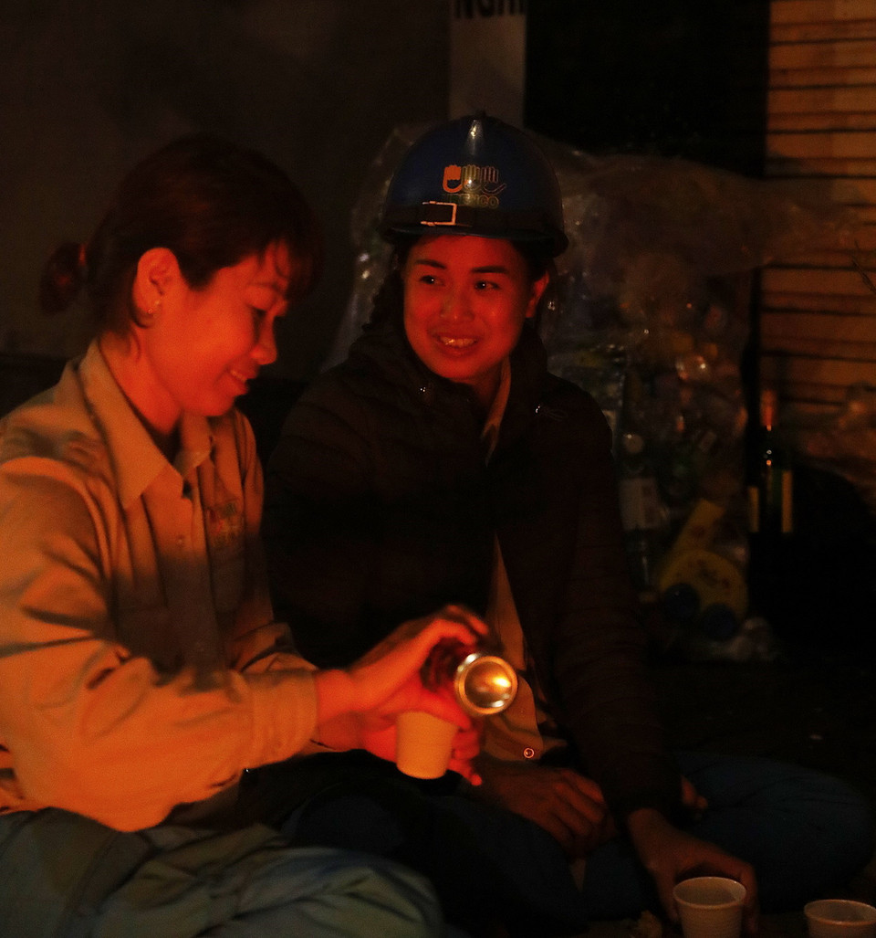 Tranh thủ giờ nghỉ giải lao, chị Nguyễn Thị Hương, nhân viên Tổ 5 phường Hàng Bài, Xí nghiệp Môi trường đô thị số 2 nhóm lửa chống rét, cùng các đồng nghiệp đón năm mới ngay trên vỉa hè phố Hàng Bài, Hoàn Kiếm. (Ảnh: Lâm Khánh/TTXVN)