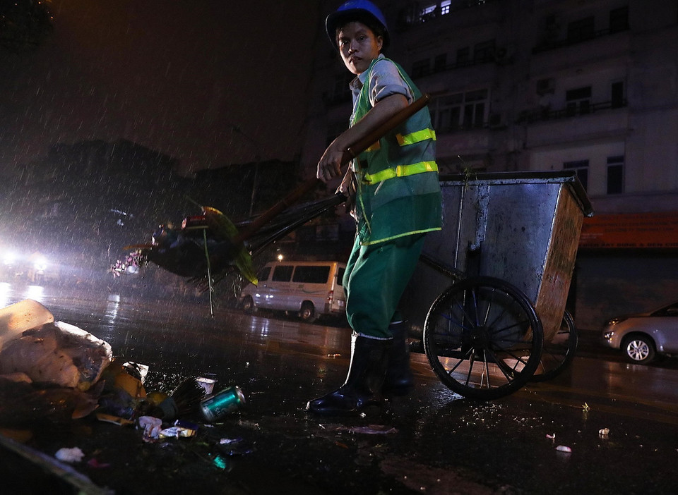 Trời mưa dài trong đêm Giao thừa khiến việc thu gom rác gặp nhiều khó khăn. (Ảnh: Lâm Khánh/TTXVN)