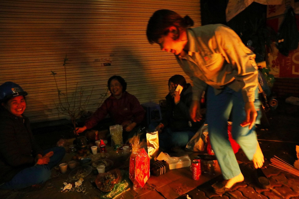 Tranh thủ giờ nghỉ giải lao, chị Nguyễn Thị Hương, nhân viên Tổ 5 phường Hàng Bài, Xí nghiệp Môi trường đô thị số 2 nhóm lửa chống rét, cùng các đồng nghiệp đón năm mới ngay trên vỉa hè phố Hàng Bài, Hoàn Kiếm. (Ảnh: Lâm Khánh/TTXVN)