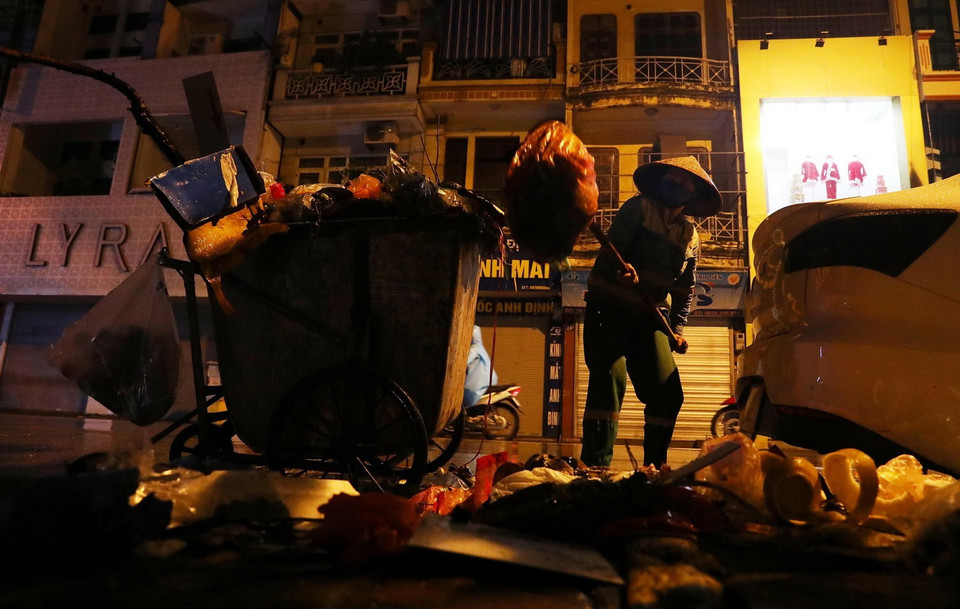 Một nhân viên vệ sinh môi trường thu gom rác thải trên phố Bạch Mai, quận Hai Bà Trưng. (Ảnh: Lâm Khánh/TTXVN)