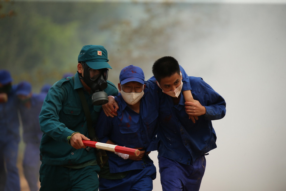 Lực lượng dân quân khẩn trương đưa người bị nạn ra khỏi khu vực nguy hiểm. (Ảnh: Dương Giang/TTXVN)