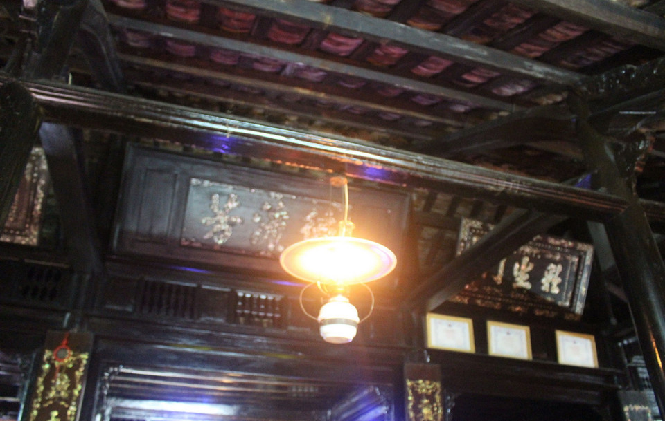  Nhà có kết cấu bằng gỗ, mái lợp ngói âm dương hoặc ngói liệt; cửa chính, cửa hông được làm bằng gỗ sao, gỗ gõ; các vì, kèo xà, con đội… được chạm khắc nhiều loại hoa văn tinh xảo. Bố cục, trang trí trong ngôi nhà cổ vẫn giữ theo nguyên bản kiểu đèn dầu ngày xưa, nhưng pha chút ánh đèn điện để phù hợp với thực tế của gia đình đang sinh sống. (Ảnh: Phan Sáu/TTXVN)