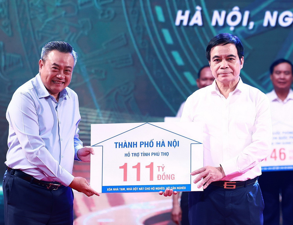 Chủ tịch UBND Thành phố Hà Nội Trần Sỹ Thanh trao tượng trưng kinh phí hỗ trợ xóa nhà tạm, nhà dột nát cho các địa phương. (Ảnh: Dương Giang-TTXVN)