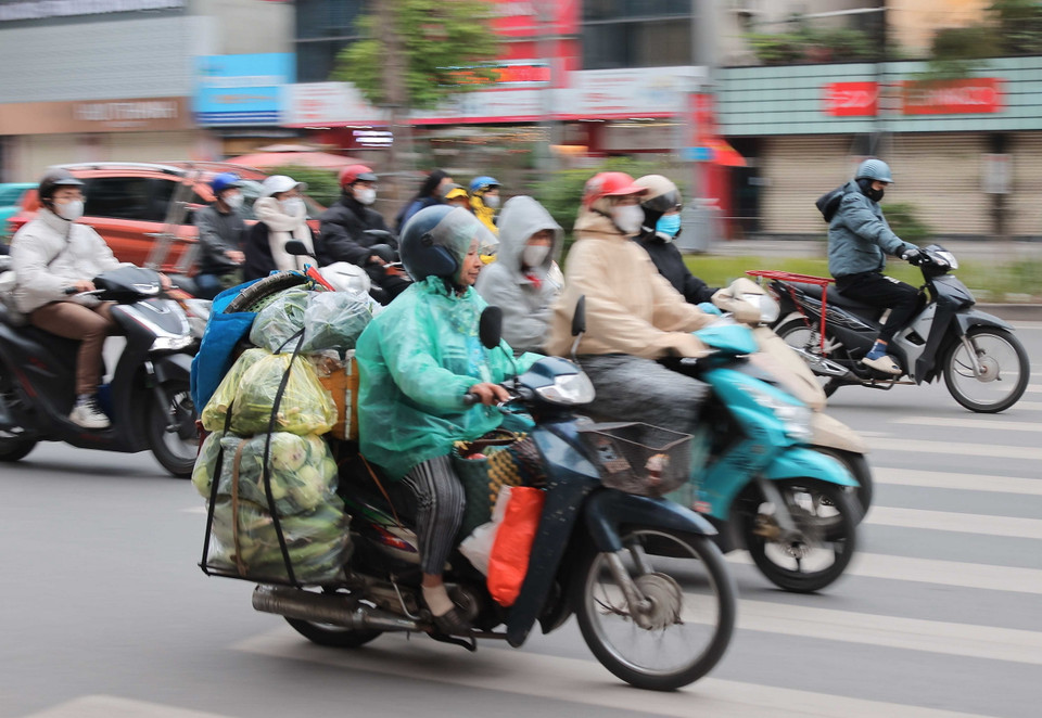Để chống lại cái lạnh, ngoài mặc đồ ấm, người lao động, buôn bán ngoài trời còn mặc thêm áo mưa để chống mưa, rét. (Ảnh: Hoàng Hiếu/TTXVN)