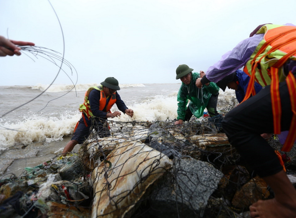 Lực lượng của huyện, xã tích khẩn trương khắc phục điểm sạt lở tại kè Cẩm Nhượng, huyện Cẩm Xuyên. (Ảnh: Minh Quyết/TTXVN)