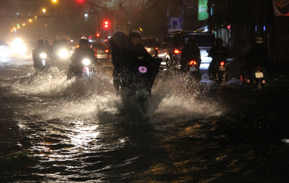 Các phương tiện lưu thông trên đường ngập nước. (Ảnh: Xuân Dự/TTXVN)