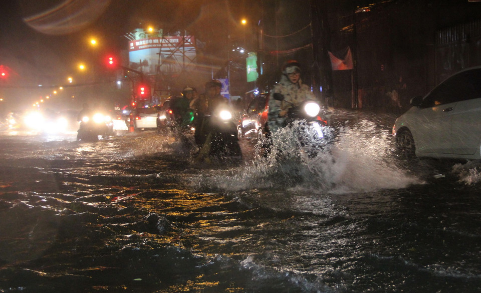 Các phương tiện lưu thông trên đường ngập nước. (Ảnh: Xuân Dự/TTXVN)