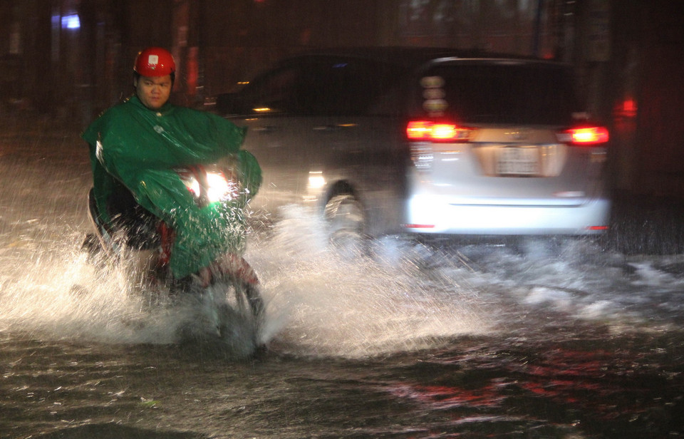 Các phương tiện lưu thông trên đường ngập nước. (Ảnh: Xuân Dự/TTXVN)