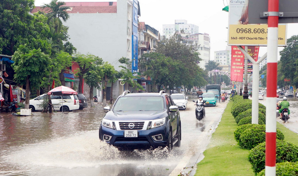 Ôtô lưu thông trên đường ngập nước tại đường Nguyễn Tất Thành, thành phố Vĩnh Yên. (Ảnh: Hoàng Hùng/TTXVN)