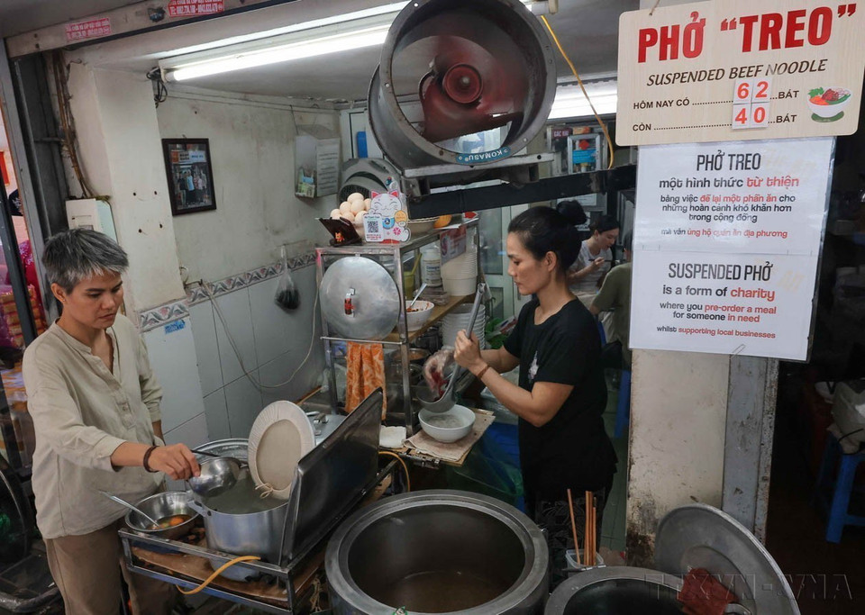 Mô hình phở "treo"của chị Lệ (bên trái) tại 14 phố Bảo Khánh, quận Hoàn Kiếm, Hà Nội nhằm giúp đỡ những người gặp khó khăn, người già, neo đơn, người khuyết tật và trẻ có hoàn cảnh khó khăn có bữa ăn ấm lòng. (Ảnh: Hoàng Hiếu/TTXVN)