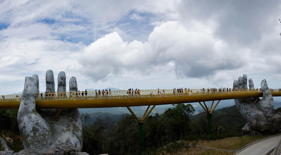 Cầu Vàng nằm ở khu vực vườn Thiên Thai của Sun World Ba Na Hills. Cầu được kết nối với nhà ga Marseille và Bordeaux để đưa khách từ khu vực chân núi hay làng Pháp thăm vườn hoa. Giữa không trung, cây cầu như một dải lụa vàng rực rỡ. (Ảnh: Trọng Đạt/TTXVN)