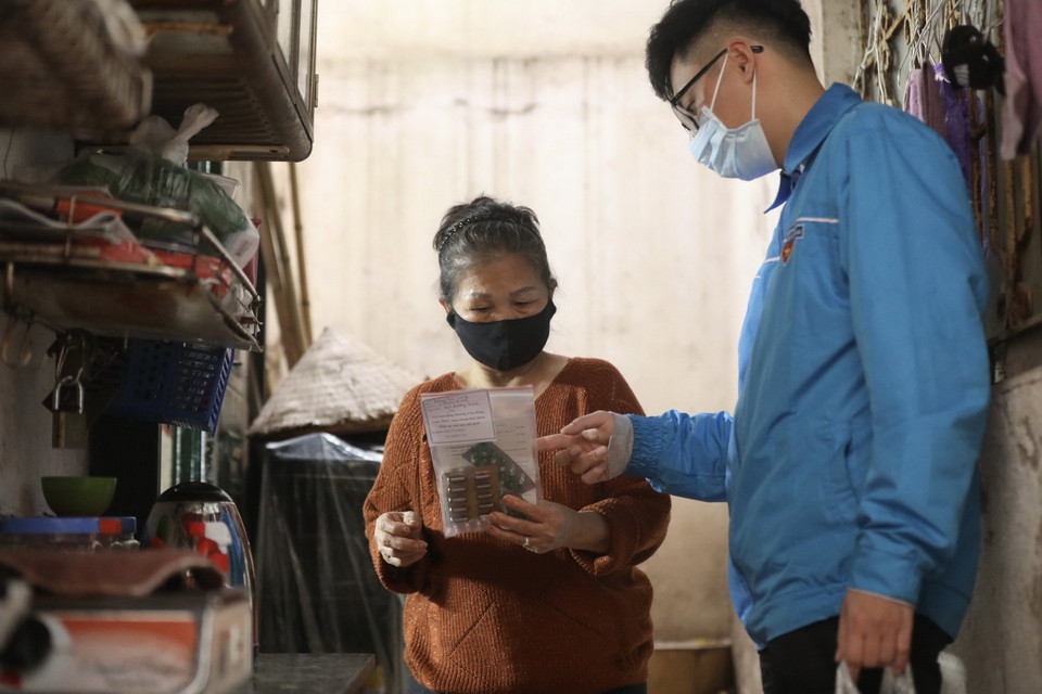 Đoàn viên thanh niên Nguyễn Viết Long đến phát thuốc cho gia đình có bệnh nhân F0 điều trị tại nhà. (Ảnh: Minh Quyết/TTXVN)