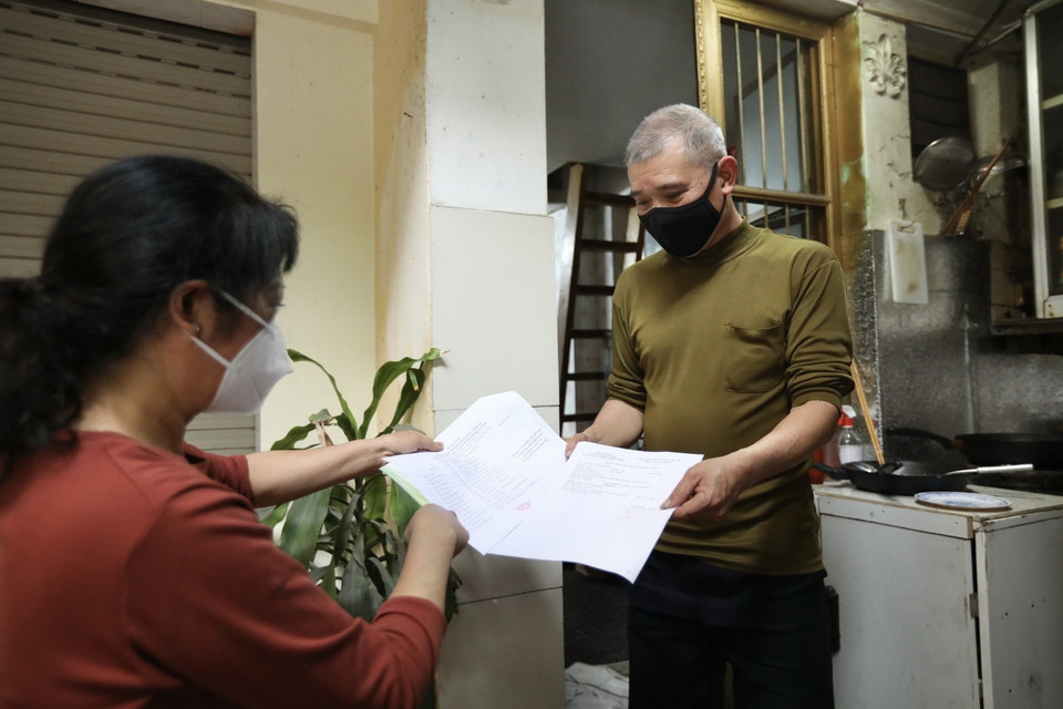 Bà Nguyễn Thị Thanh Hiền, Tổ phó tổ dân phố số 3, phường Cửa Đông trao giấy chứng nhận cho các trường hợp F0 đã khỏi bệnh điều trị tại nhà. (Ảnh: Minh Quyết/TTXVN)