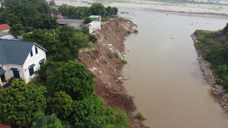Sạt lở nghiêm trọng làm hai ngôi nhà của người dân khu 2, xã Tu Vũ bị lở xuống ngòi Lạt. (Ảnh: Tạ Toàn/TTXVN)
