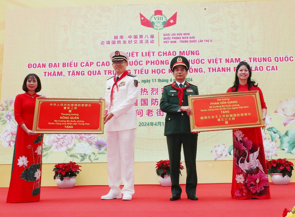 Bộ trưởng Quốc phòng Phan Văn Giang và Bộ trưởng Quốc phòng Trung Quốc Đổng Quân tặng quà lưu niệm cho Trường Tiểu học Kim Đồng (thành phố Lào Cai). (Ảnh: Trọng Đức/TTXVN)