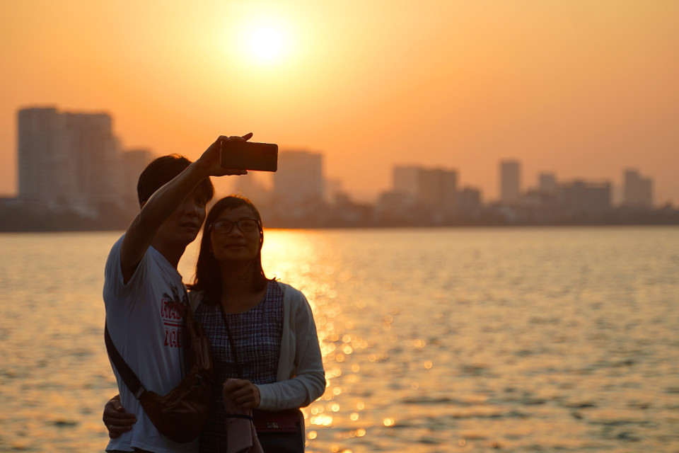 Các bạn trẻ lưu lại khoảng khắc mùa Thu Hà Nội tại hồ Tây. (Ảnh: Khánh Hòa/TTXVN)