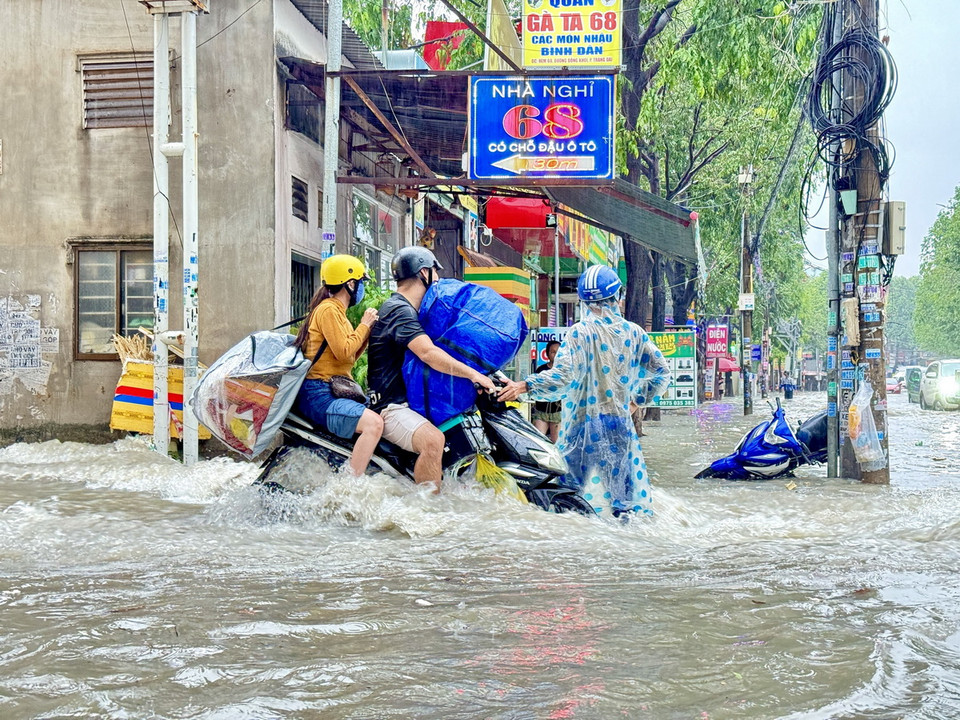 Người dân chật vật di chuyển qua điểm ngập tại ngã ba Trảng Dài (thành phố Biên Hòa, Đồng Nai). (Ảnh: Lê Xuân/TTXVN)