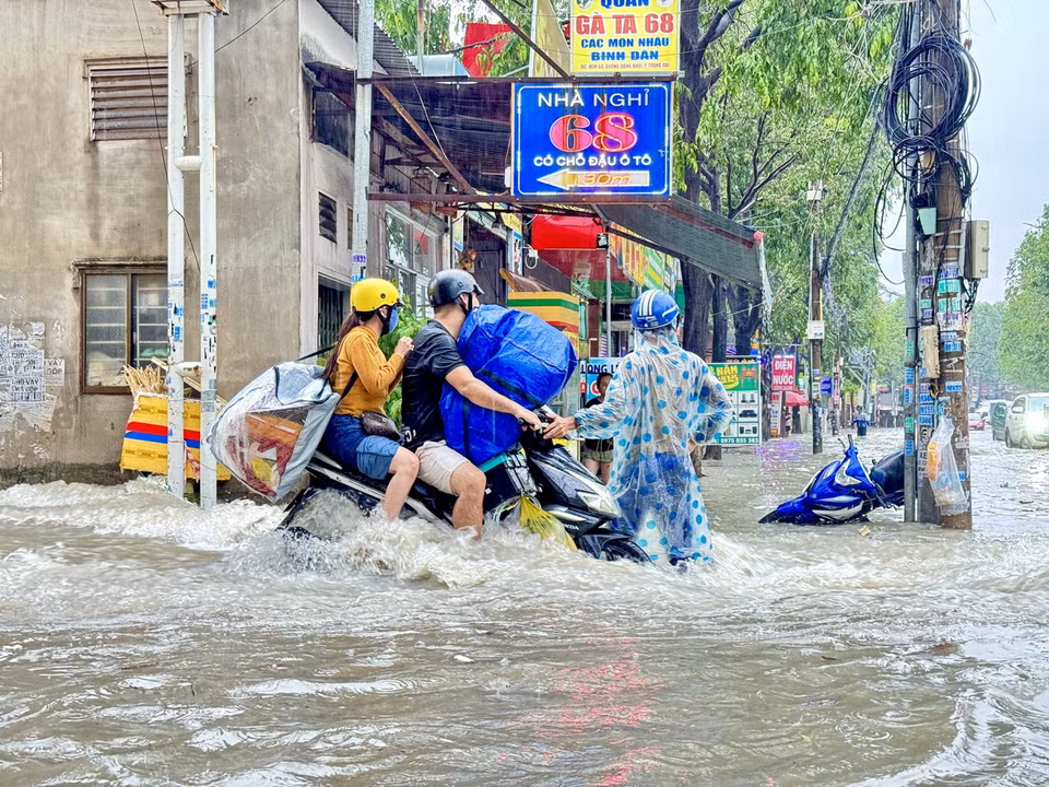 Người dân chật vật di chuyển qua điểm ngập tại ngã ba Trảng Dài (thành phố Biên Hòa, Đồng Nai). (Ảnh: Lê Xuân/TTXVN)