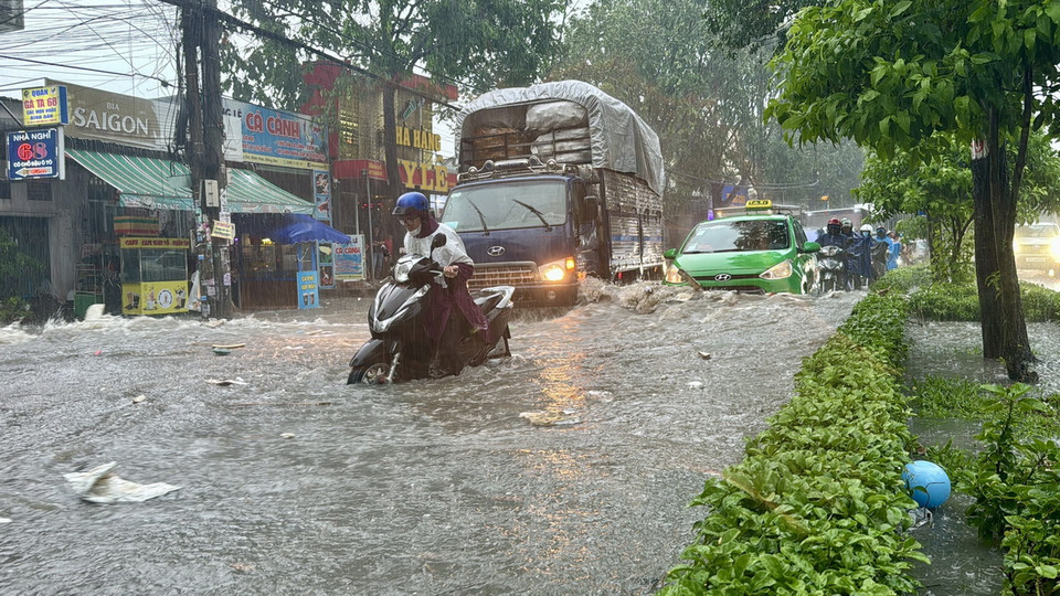 Người dân di chuyển qua điểm ngập tại ngã ba Trảng Dài (thành phố Biên Hòa, Đồng Nai). (Ảnh: Lê Xuân/TTXVN)