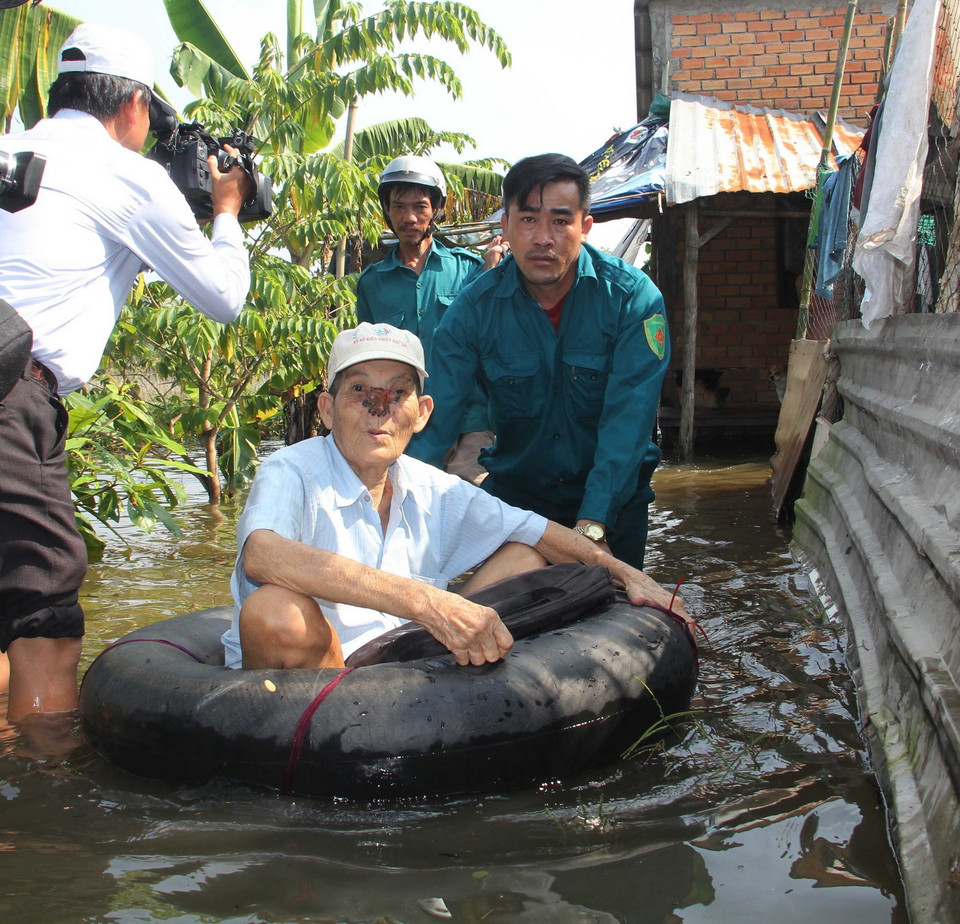 Sơ tán người già ra khỏi khu vực bị ngập nặng. (Ảnh: Thanh Liêm/TTXVN)