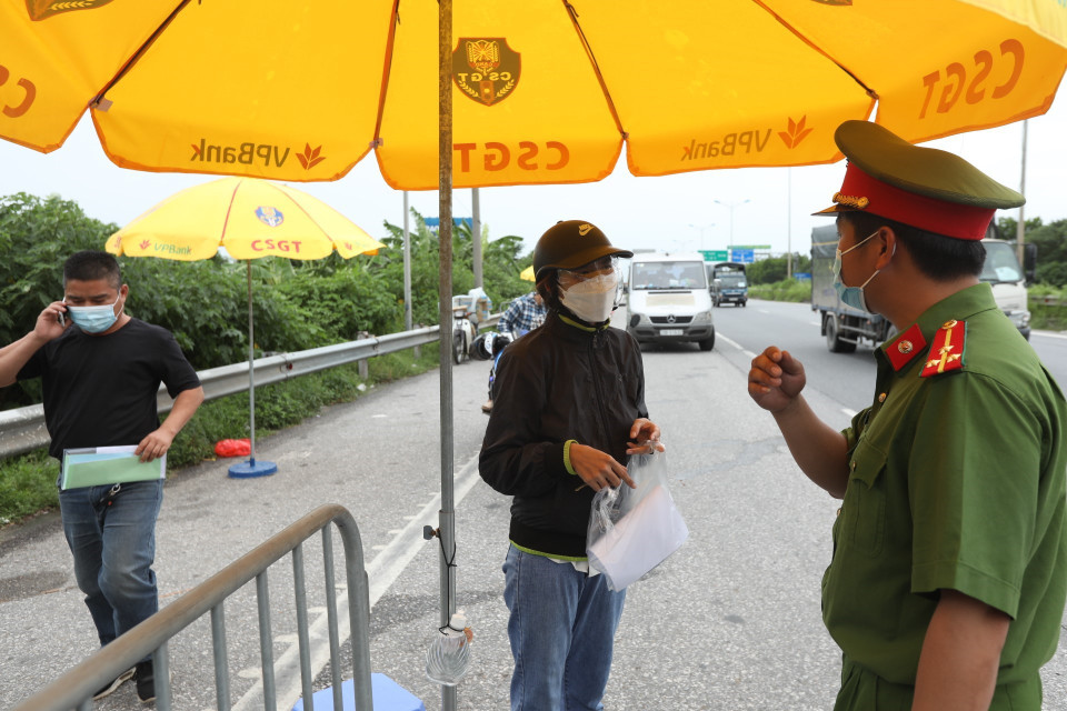 Lực lượng chức năng kiểm tra thông tin, điều kiện của người và phương tiện khi qua chốt kiểm soát cầu Phù Đổng. (Ảnh: Minh Quyết/TTXVN)