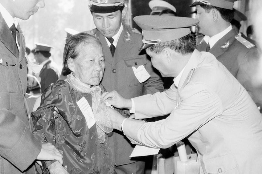 Thay mặt lực lượng vũ trang, thiếu tướng Nguyễn Răng gắn kỷ niệm chương cho các mẹ tại Lễ trao tặng danh hiệu Bà mẹ Việt Nam anh hùng và Anh hùng lực lượng vũ trang nhân dân của Thành phố Hồ Chí Minh (1995). (Ảnh: Tứ Hải/TTXVN)