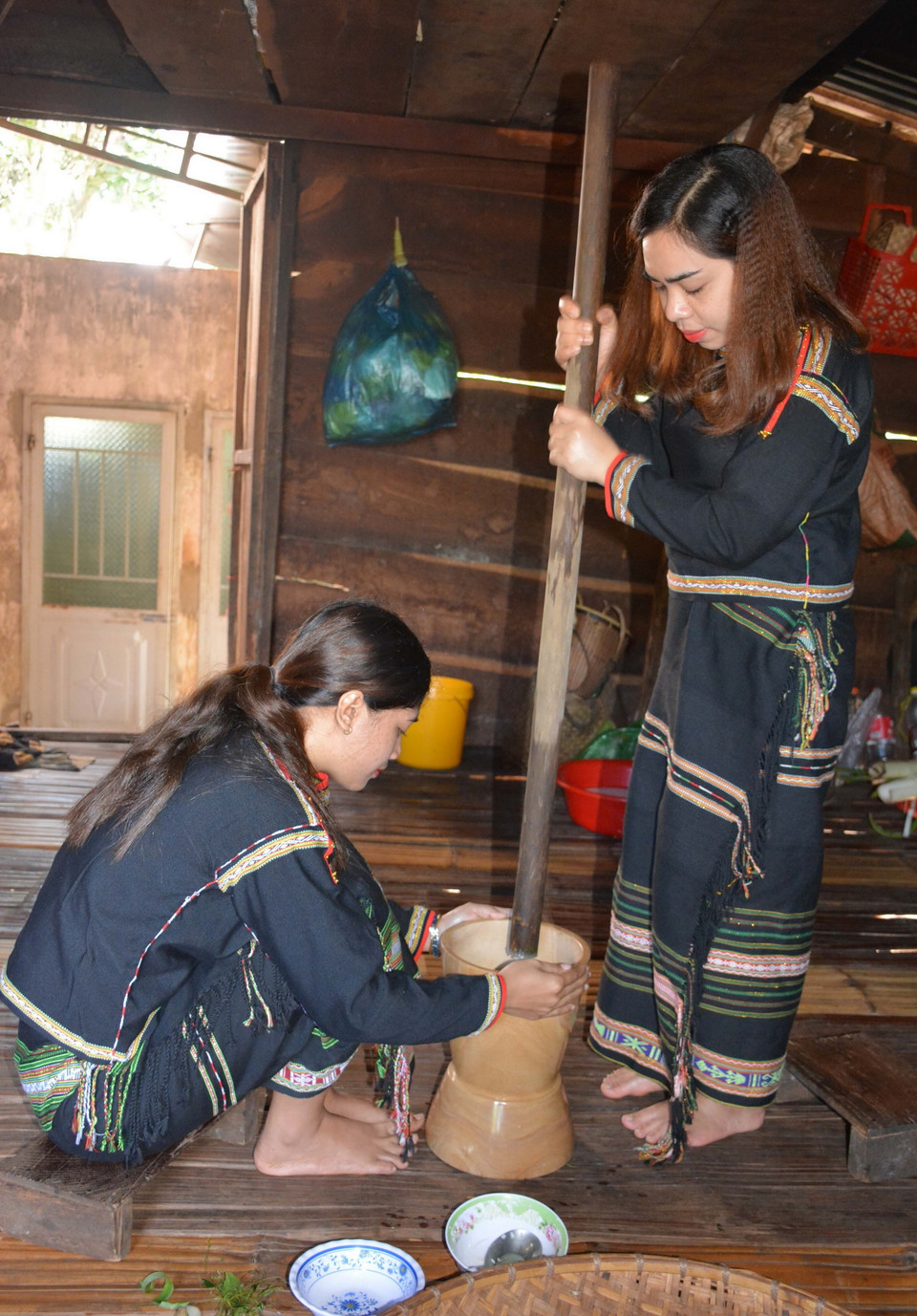 Hai cô gái Ê Đê giã hỗn hợp lá yao và bột gạo, hai nguyên liệu quan trọng nhất, không thể thay thế của món canh bột lá yao. Gạo sau khi ngâm thì để ráo nước, sau đó giã chung với lá yao cho tới khi nát đều, mịn. (Ảnh: Hoài Thu/TTXVN)