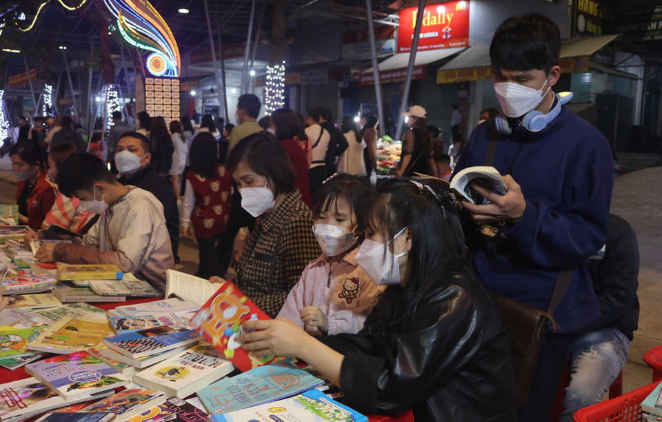  Người dân tham gia hoạt động đọc sách trong không gian phố đi bộ Kim Đồng. (Ảnh: Chu Hiệu/TTXVN)