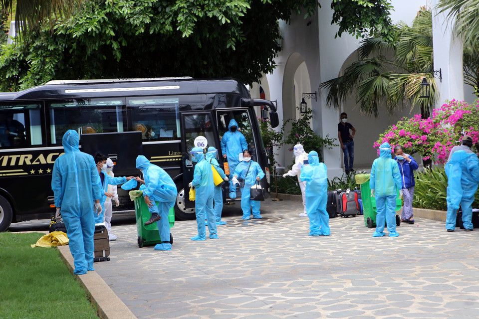 Công dân được đưa về cách ly tại khách sạn thực hiện thay đồ bảo hộ và các biện pháp phòng chống dịch trước khi vào lưu trú cách ly. (Ảnh: Trần Lê Lâm/TTXVN)