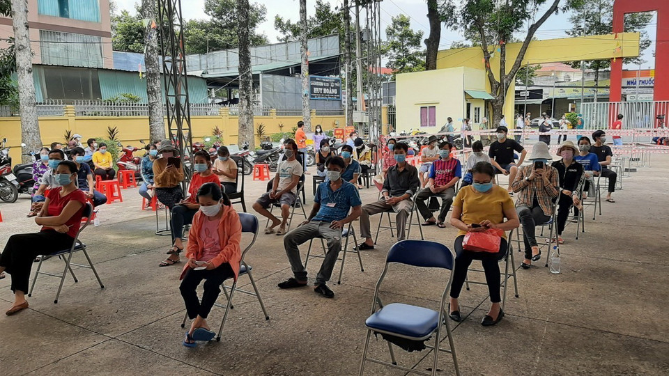 Người dân ngồi xếp hàng để được tiêm vaccine Vero Cell tại điểm tiêm Trung tâm văn hóa phường Phú Lợi, thành phố Thủ Dầu Một, tỉnh Bình Dương. (Ảnh: Chí Tưởng/TTXVN) 
