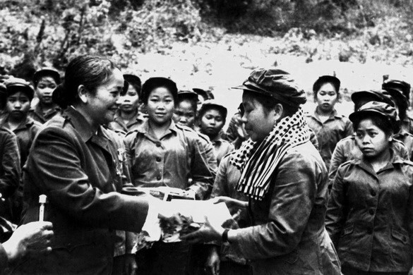 Công tác tuyên giáo đã kết hợp giáo dục chủ nghĩa yêu nước với tinh thần quốc tế vô sản, Giúp bạn là tự giúp mình, động viên quân và dân ta thực hiện liên minh chiến đấu giữa ba nước Đông Dương chống Mỹ. Trong ảnh: Chủ tịch Hội Liên hiệp Phụ nữ miền Nam Việt Nam Nguyễn Thị Định trao tặng phẩm cho đại đội nữ pháo binh trong chuyến thăm hữu nghị vùng giải phóng Lào (25-29/4/1974). (Ảnh: Tư liệu TTXVN)